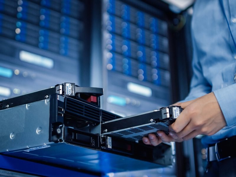 In the Modern Data Center: IT Engineer Installs New HDD Hard Drive and Other Hardware into Server Rack Equipment. IT Specialist Doing Maintenance, Running Diagnostics and Updating Hardware.